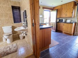 A bathroom with a toilet and sink next to a kitchen with wooden cabinets and an open door at Dolphin Bach in Dolphin
