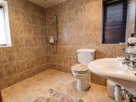 A bathroom with a shower, toilet, sink, windows with blinds and a beige tiled floor and walls at Dolphin Bach in Dolphin