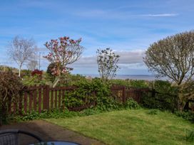 A garden with a wooden fence trees and plants overlooking water at Dolphin Bach in Dolphin