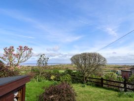 A garden with trees bushes and a wooden fence overlooking fields and hills at Dolphin Bach in Dolphin