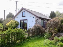 A small white house with brown trim and a fenced garden with bushes and grass at Dolphin Bach in Dolphin