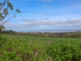 A rural landscape with green fields trees and a wooden fence with a body of water in the distance at Dolphin Bach in Dolphin
