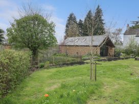 A garden with green grass trees and a stone building with a slate roof at The Cart Shed in Barwick near Yeovil Somerset