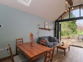 A dining table with chairs a gray sofa and a wooden coffee table in a room with large glass doors opening to a patio at The Cart Shed in Barwick near Yeovil Somerset