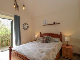 A bedroom with a wooden bed and bedside tables with lamps at The Cart Shed in Barwick near Yeovil Somerset