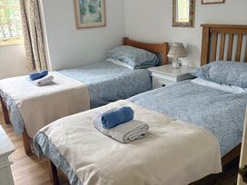 A bedroom with two beds and a bedside table at Sunlight Cottage St Erme near Truro