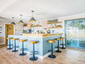 A bar with stools and shelves at Lodge 62 at Riviera Bay Coastal Retreat Brixham