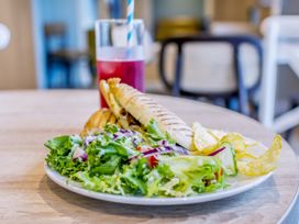 A plate of salad, sandwich, and chips with a drink at Lodge 63 at Riviera Bay Coastal Retreat in Brixham