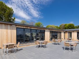 A wooden building with tables and chairs on a deck at Lodge 69 at Riviera Bay Coastal Retreat Brixham