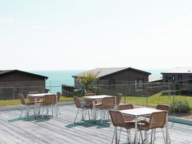 An outdoor area with tables and chairs near the ocean at Chalet 7 at Landscove Holiday Park Brixham