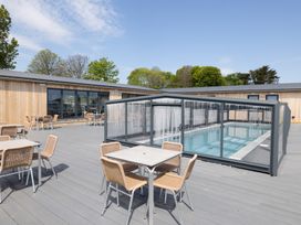 An outdoor area with a pool enclosure and seating at Chalet 7 at Landscove Holiday Park in Brixham