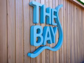 A blue sign that says The Bay on a wooden wall at Lodge 73 at Riviera Bay Coastal Retreat Brixham