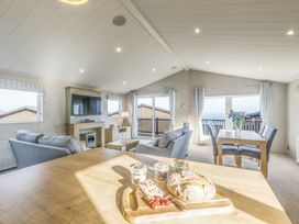 A living room with a sofa, television, and dining table at Lodge 73 at Riviera Bay Coastal Retreat, Brixham