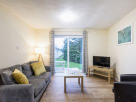 A living room with a sofa, television, and sliding door at Chalet 27 at Landscove Holiday Park Brixham