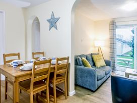 A dining room with a table and chairs and a living area at Chalet 32 at Landscove Holiday Park Brixham