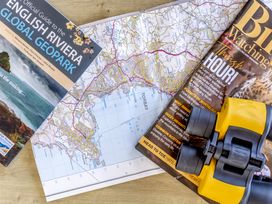 A map, a guide to the English Riviera, a bird watching magazine, and binoculars at Lodge 9 at Landscove Holiday Park, Brixham