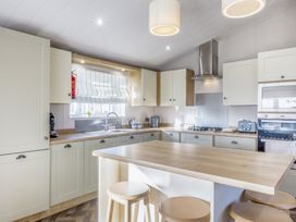 A kitchen with an island and stools at Lodge 9 at Landscove Holiday Park Brixham