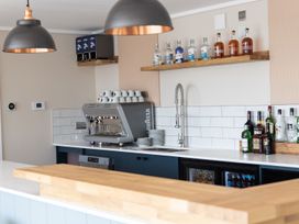 A kitchen with a coffee machine and shelves of bottles at Lodge 9 at Landscove Holiday Park in Brixham