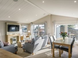 A living room with a sofa, table, and television at Lodge 11 at Landscove Holiday Park in Brixham