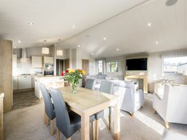 A living room and kitchen area with a dining table and sofa at Lodge 11 at Landscove Holiday Park Brixham