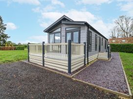 A modern prefabricated house with a small deck and stairs surrounded by grass and gravel paths at Wurzburc in Swaffham