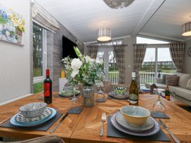 A dining table set with plates bowls wine glasses and bottles in a living area with sofas windows and curtains at Wurzburc in Swaffham