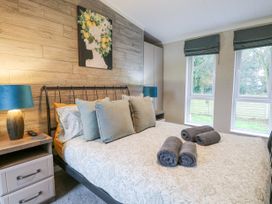 A bedroom with a bed and pillows bedside tables with lamps and two windows at Wurzburc in Swaffham