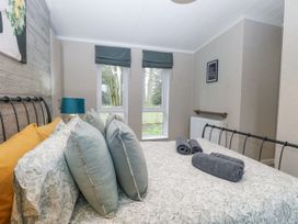 A bedroom with a bed with floral bedding and multiple pillows a blue lamp and two windows at Wurzburc in Swaffham