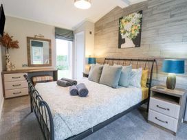 A bedroom with a double bed with pillows and towels two bedside tables with lamps a desk with a mirror stool and window at Wurzburc in Swaffham