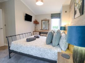 A bedroom with a bed a television on the wall a desk with a mirror and a lamp at Wurzburc in Swaffham