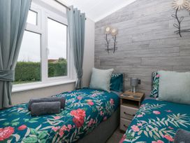 A bedroom with two single beds with floral bedding and a window with curtains at Wurzburc in Swaffham
