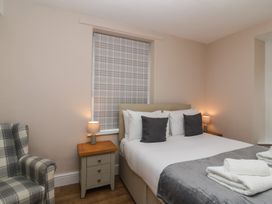 A bedroom with a bed side tables lamps and a plaid armchair at Metcalfe House in Compton Dundon