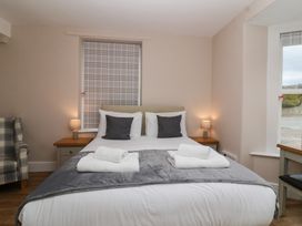 A bedroom with a bed with white and gray bedding two bedside tables lamps and a plaid armchair at Metcalfe House in Compton Dundon