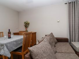 A dining table with four wooden chairs a bottle of wine two glasses a sideboard with flowers and a brown sofa at Metcalfe House in Compton Dundon