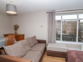 A living room with a sofa ottoman floral arrangement and dining table near a window at Metcalfe House in Compton Dundon