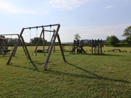 A playground with swings and a play structure at Metcalfe House in Compton Dundon