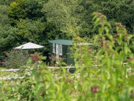 A shepherd's hut with an umbrella in outdoor space at Collen Aberaeron