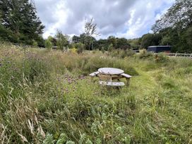 A garden with a table and benches surrounded by grass and flowers at Bedwen in Aberaeron