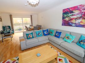 A living room with a sofa and dining area at 15 Lawnswood in Saundersfoot