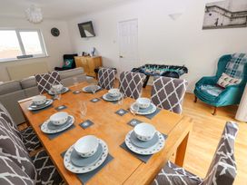 A dining room with a table set for meals at 15 Lawnswood in Saundersfoot