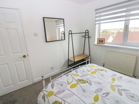 A bedroom with a bed, mirror and window at 15 Lawnswood Saundersfoot