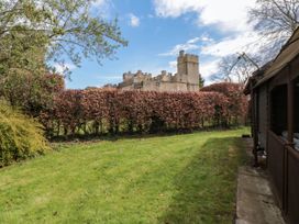 A garden with grass lawn and hedge with a stone castle behind at Snape Castle Garden Lodge Snape near Bedale
