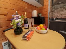 A kitchen table with a vase of flowers fruit bowl bottle of champagne and two glasses at Snape Castle Garden Lodge in Snape near Bedale