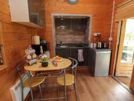 A kitchen with a small dining table and chairs a mini fridge toaster kettle and cabinet at Snape Castle Garden Lodge Snape near Bedale
