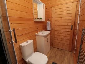 A bathroom with a toilet sink mirror towel and wooden walls at Snape Castle Garden Lodge Snape near Bedale
