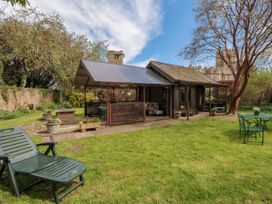 A garden with a wooden cabin with a covered porch and outdoor furniture at Snape Castle Garden Lodge in Snape near Bedale