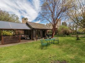 A garden with a green metal table and chairs near a wooden structure and trees at Snape Castle Garden Lodge in Snape near Bedale