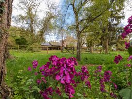 A garden with purple flowers green grass trees and a wooden fence at Snape Castle Garden Lodge in Snape near Bedale