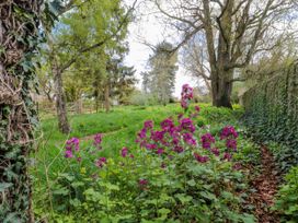 A garden area with purple flowers green grass and trees at Snape Castle Garden Lodge Snape near Bedale