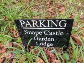 A black parking sign with white text placed in grass and fallen leaves at Snape Castle Garden Lodge Snape near Bedale